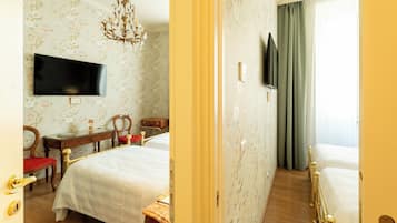 Ein Hotelzimmer mit zwei Betten, einem Fernseher, einem Schreibtisch mit Stuhl und einer Kandelaber.