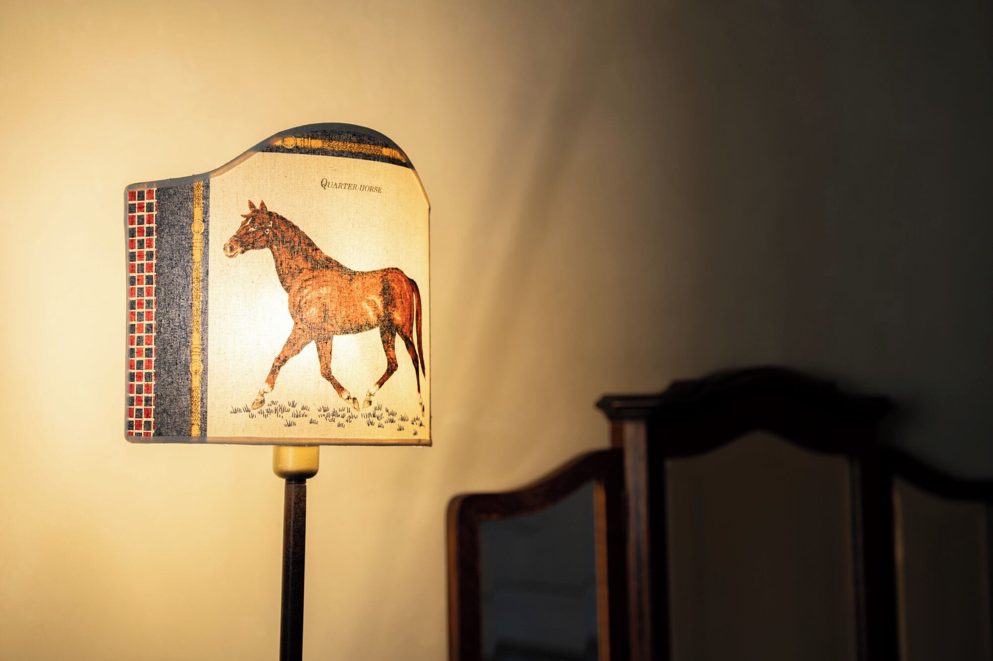 Una lámpara con un diseño de caballo en su pantalla.