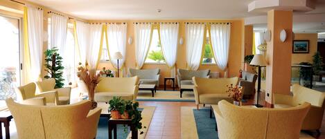 A spacious living room with yellow armchairs, a coffee table, and a large window with curtains.