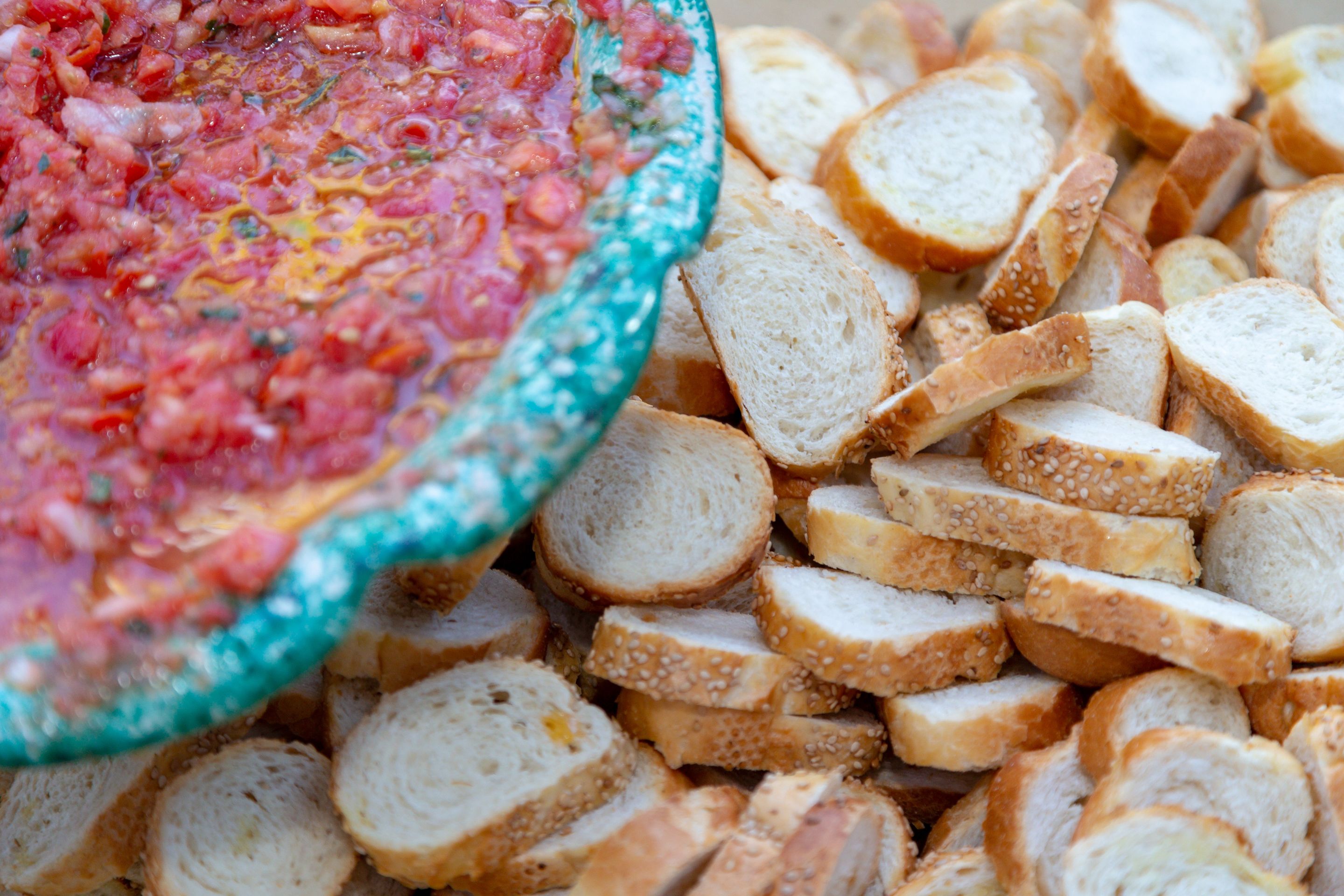A bowl of salsa and sliced bread.