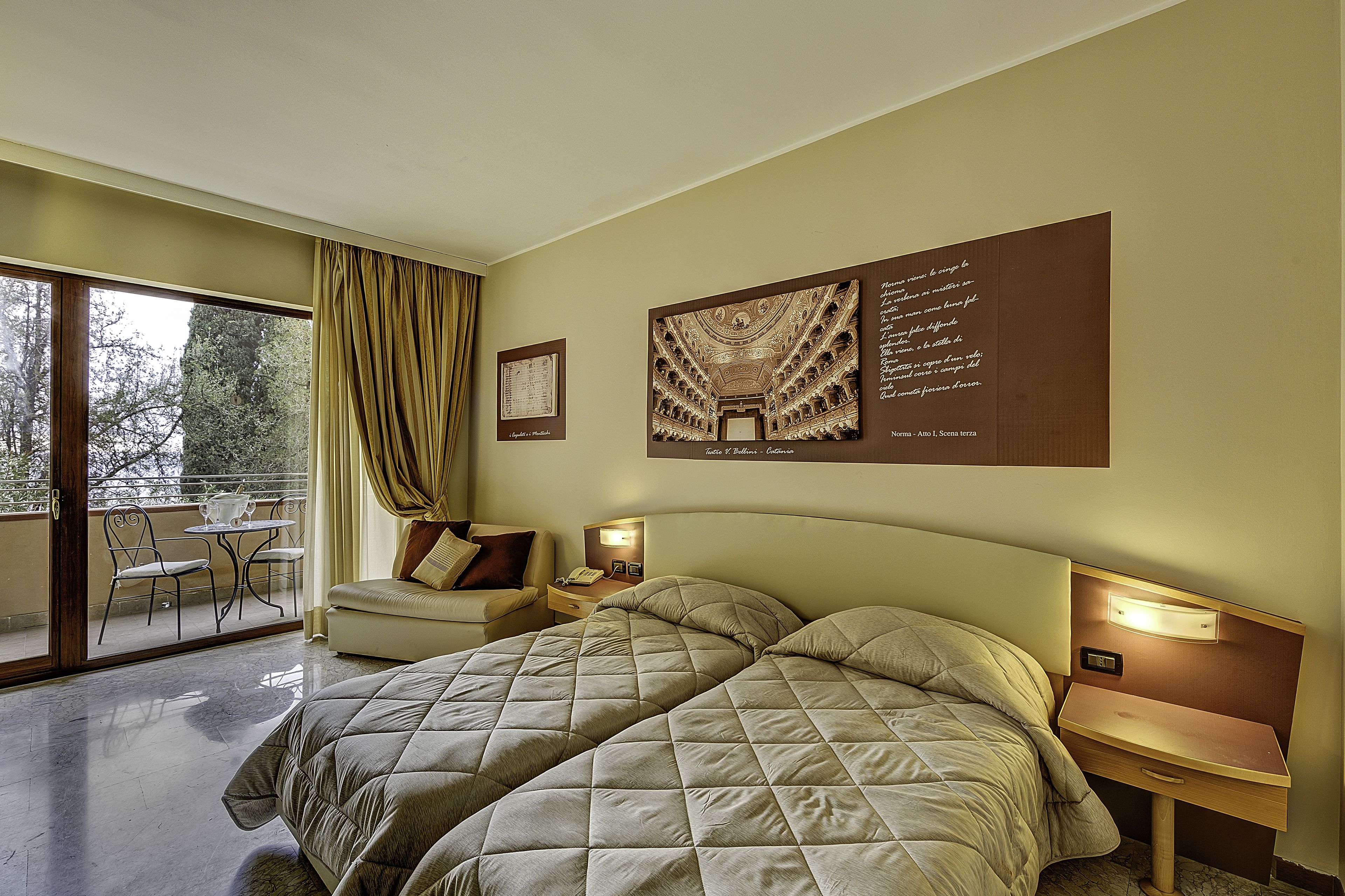 Ein Hotelzimmer mit einem großen Bett, einem Schreibtisch, einem Sessel und einem Balkon mit Tisch und Stühlen.