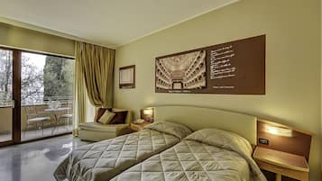 Ein Hotelzimmer mit einem großen Bett, einem Schreibtisch, einem Sessel und einem Balkon mit Tisch und Stühlen.