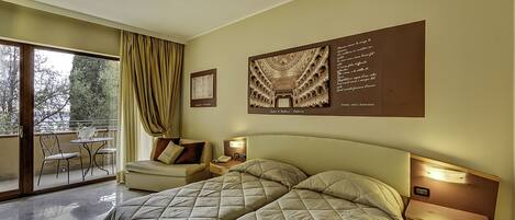 Habitación de hotel con una cama grande, un escritorio, una silla y un balcón con mesa y sillas.