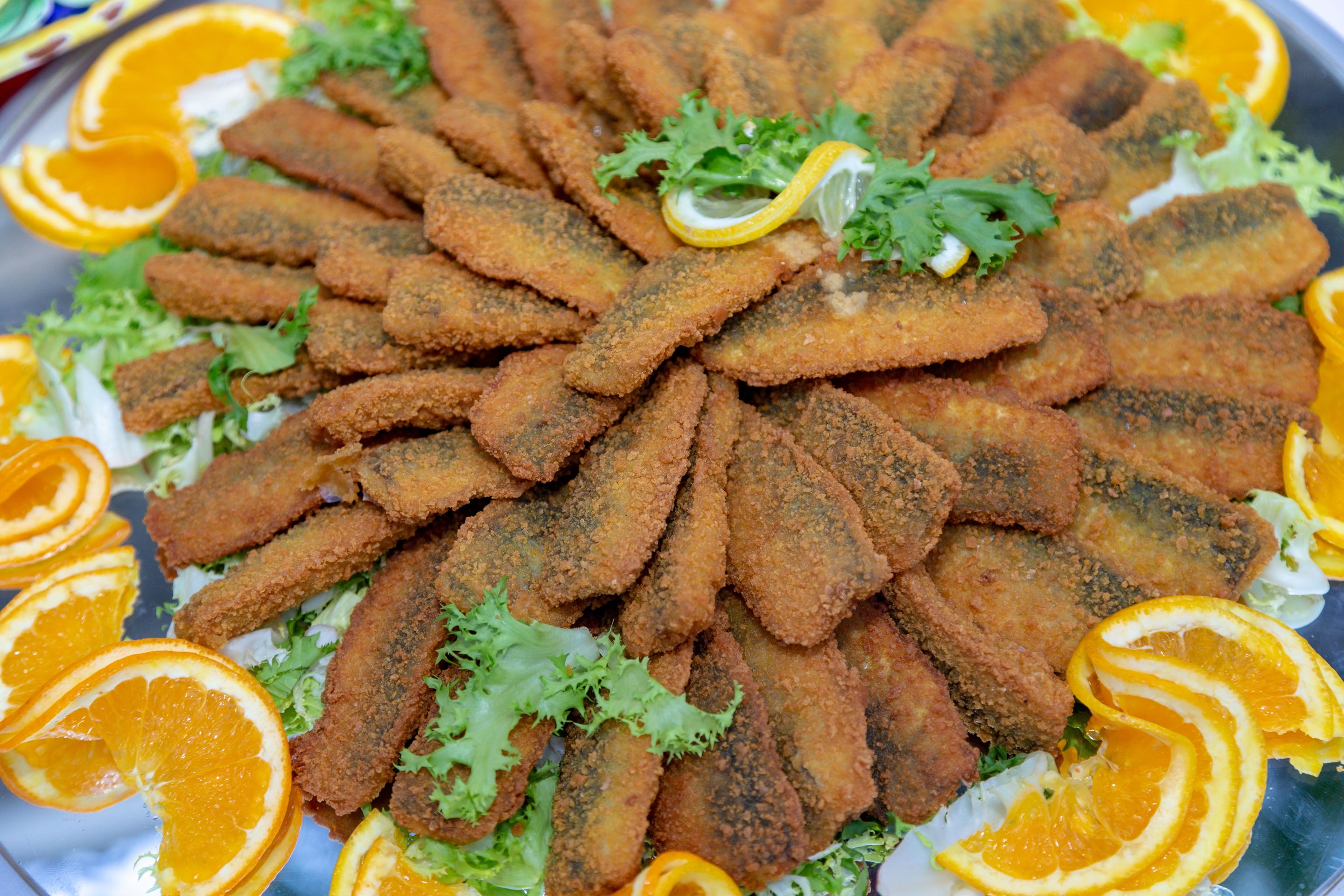 A plate of breaded and fried food garnished with orange slices and greens.