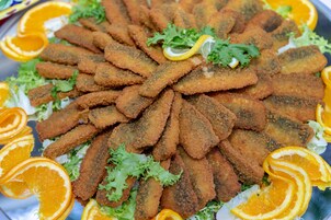 A plate of breaded and fried food garnished with orange slices and greens.