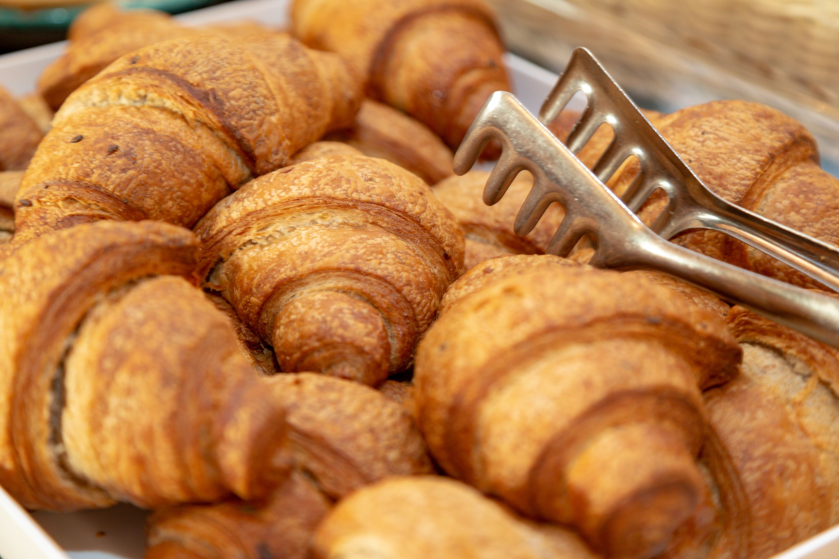 Ein Teller mit Croissants und einem Gebäckheber.
