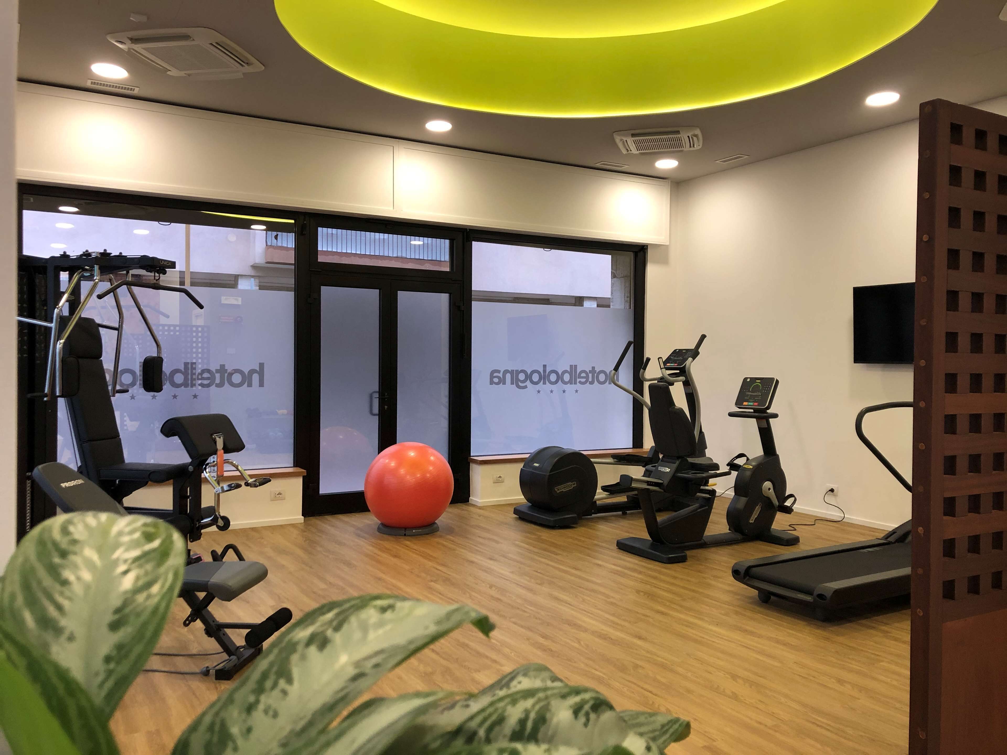 Un gimnasio con equipo de ejercicio, una pelota grande para ejercicio y una cinta de correr.