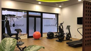 Una palestra con attrezzature per esercizi, una palla ginnastica grande e un tapis roulant.