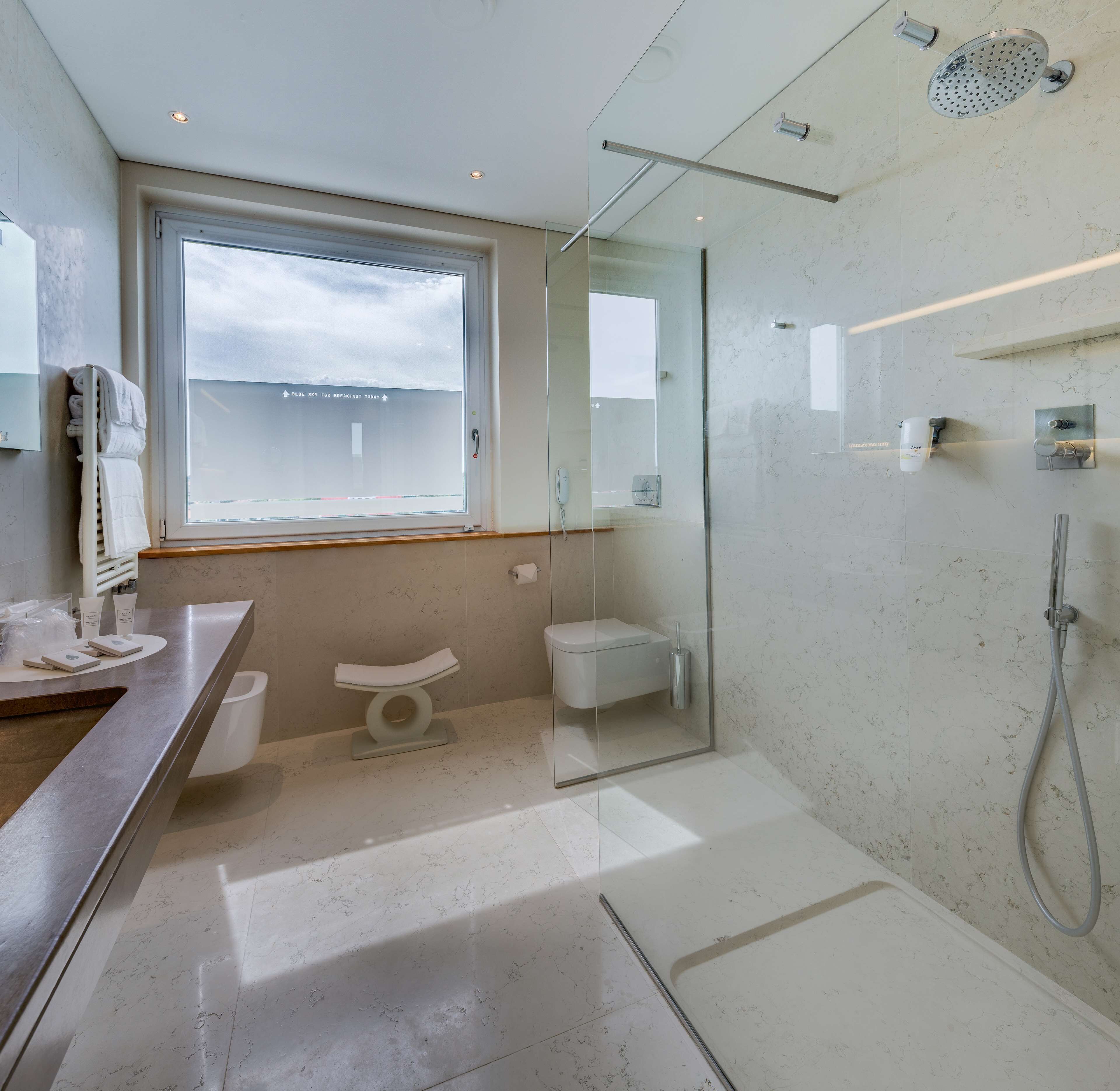Een moderne badkamer met een douchecabine van glas, een toilet en een wastafel met spiegel.