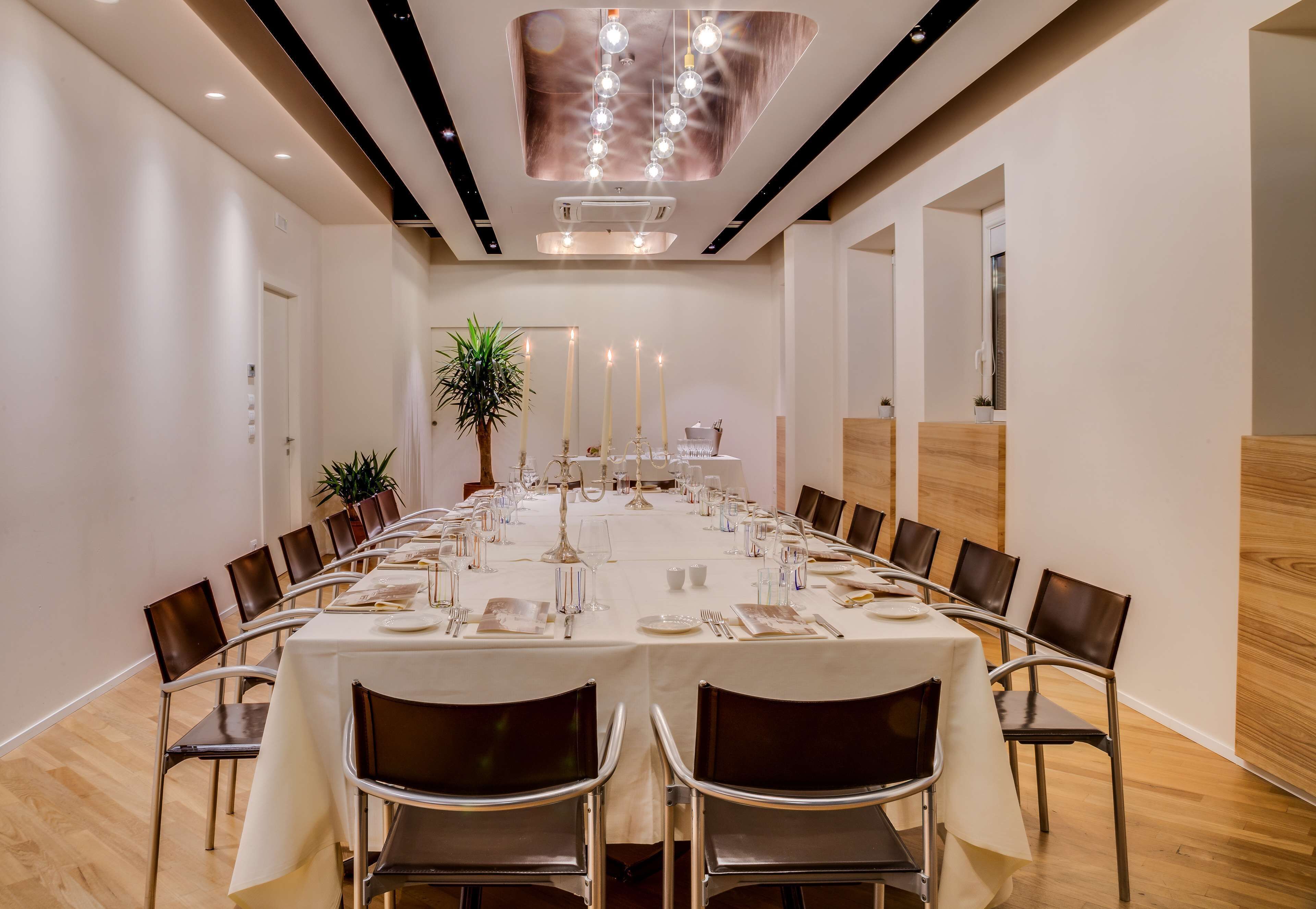A conference room with a long table set for a meeting, surrounded by chairs, with a potted plant and candles on the table.