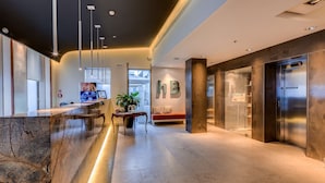 A modern lobby with a marble reception desk, a bench, a potted plant, and an elevator. - Best Western Plus Hotel Bologna (Mestre)