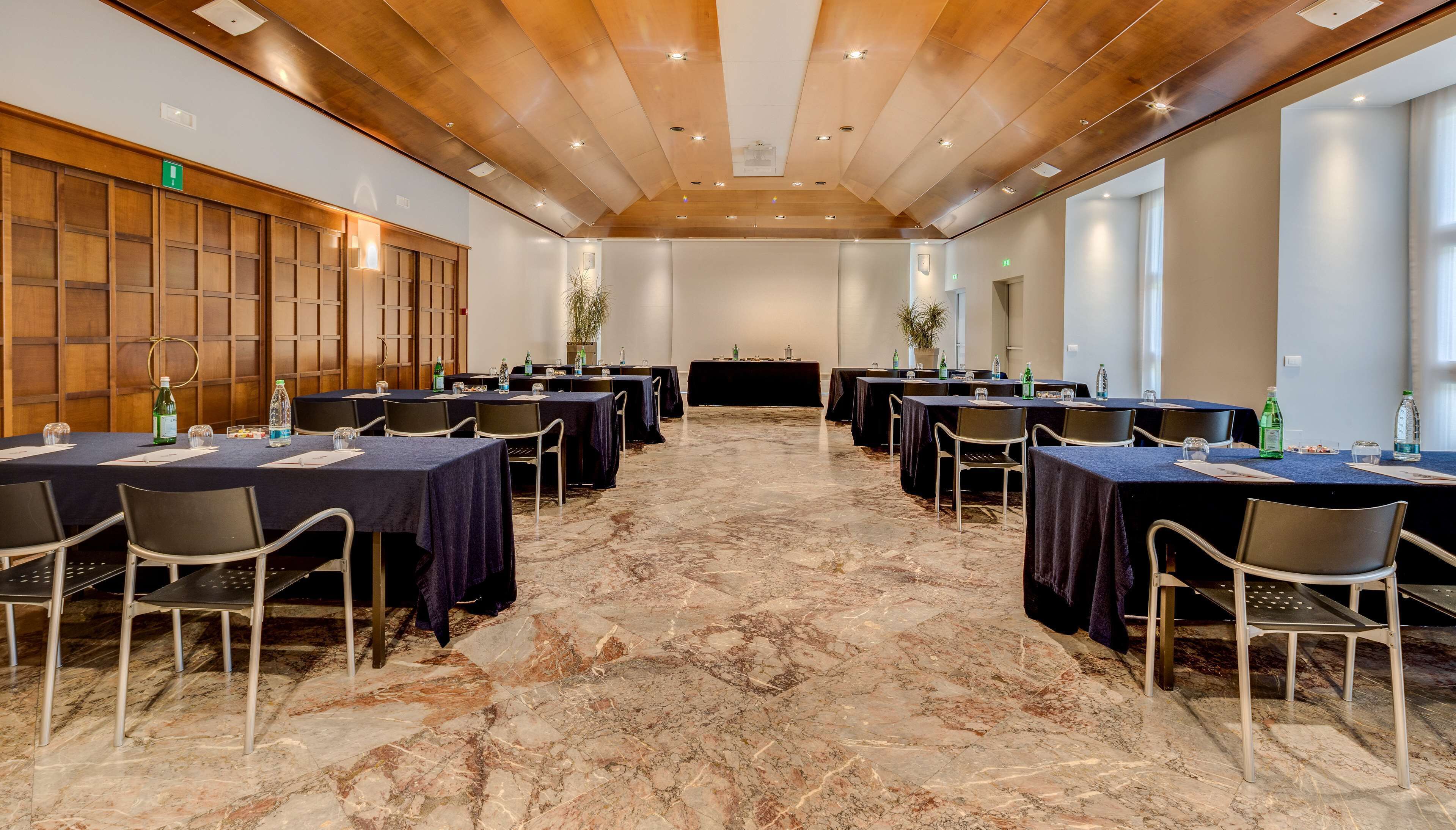 A conference room with marble flooring, wooden paneling on the walls, and tables set for meetings.
