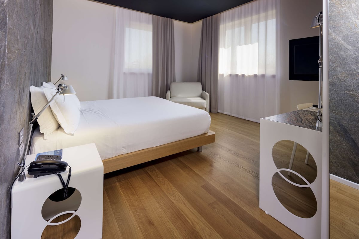 Una camera d'albergo moderna con un letto, una sedia, una scrivania e un bagno.