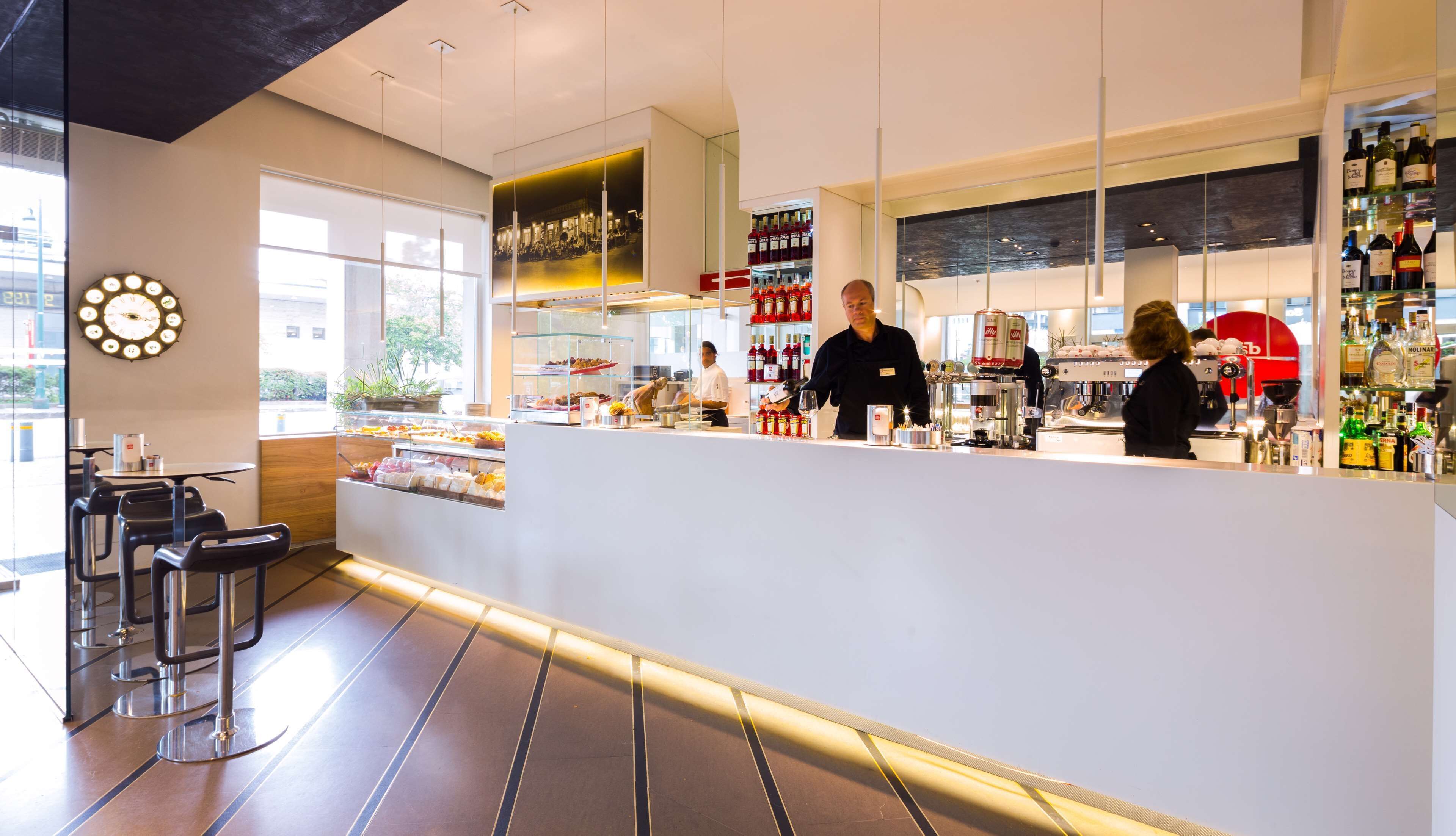 Un espace bar moderne avec un comptoir, des sièges et une grande horloge au mur.