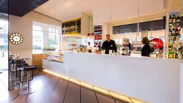 Un espace bar moderne avec un comptoir, des sièges et une grande horloge au mur.