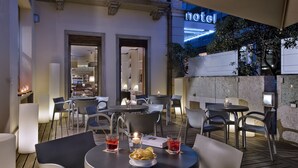 An outdoor dining area with tables and chairs, a neon sign reading "hotel", and a view of the interior through an open doorway. - Best Western Plus Hotel Bologna (Mestre)