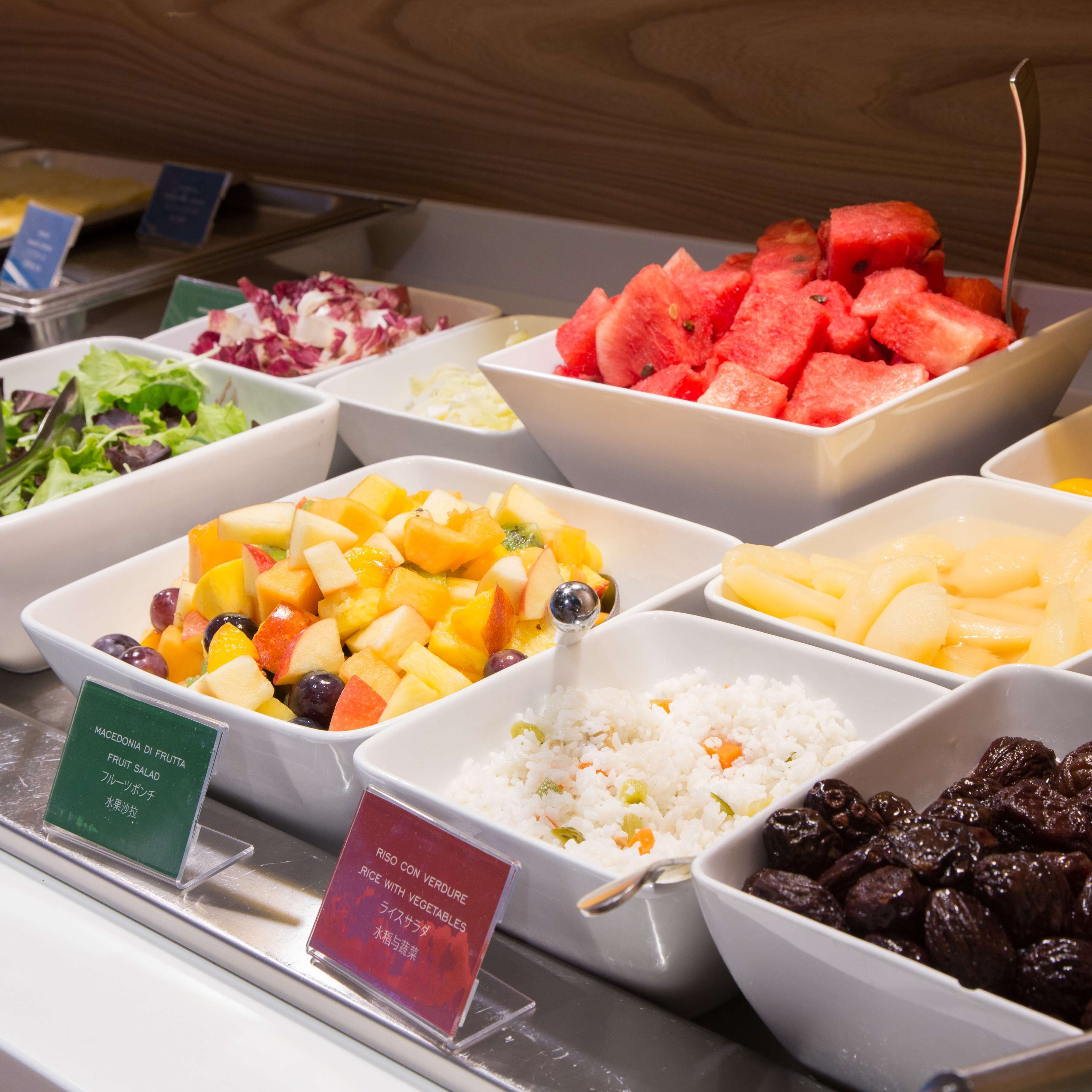 Un buffet proposant une variété de plats, notamment une salade de fruits, du riz aux légumes et de la pastèque.