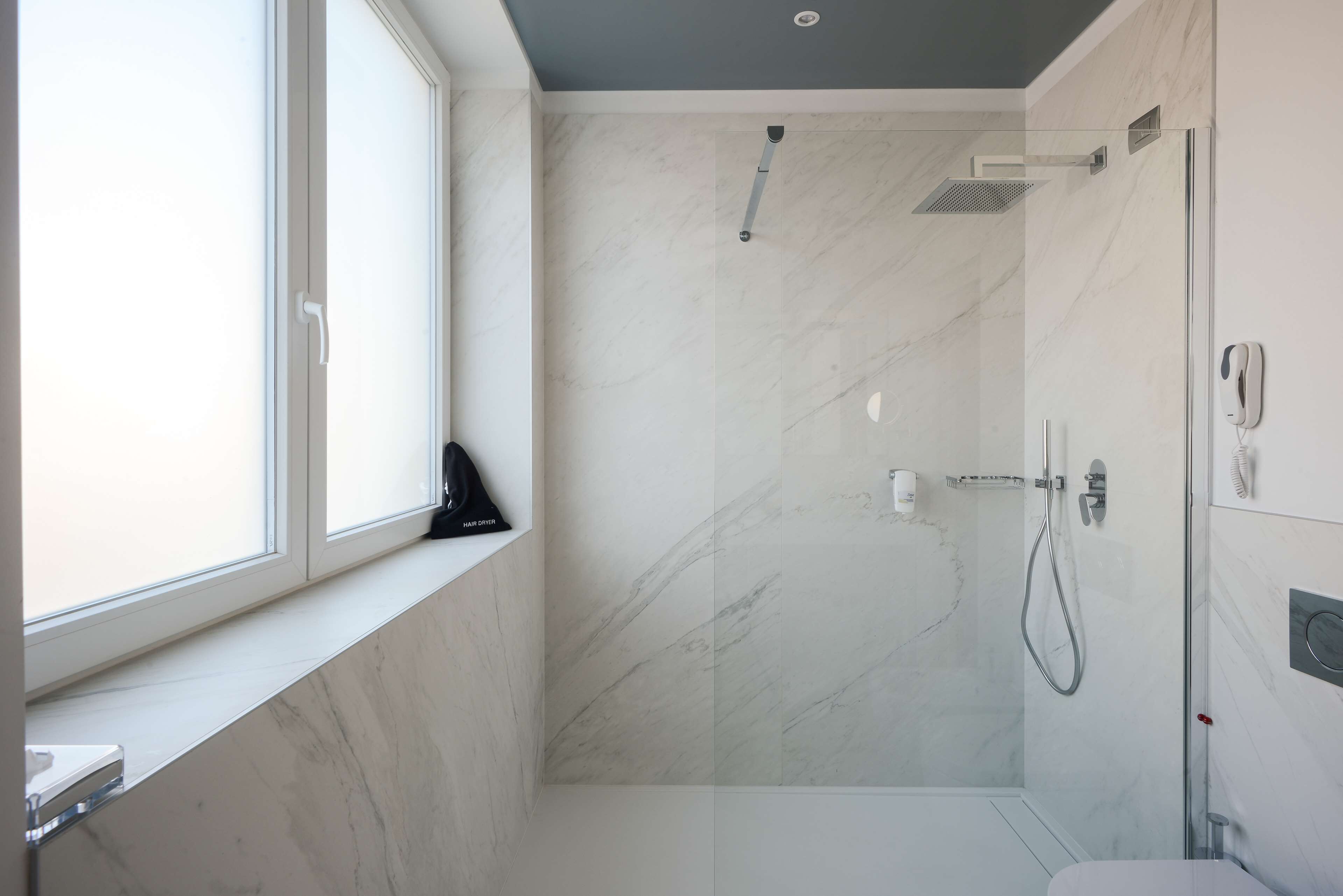 A modern bathroom with a shower, a toilet, and a window.