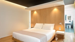 A modern hotel room with a large bed, wooden headboard, bedside tables, and a visible bathroom in the background. - Best Western Plus Hotel Bologna (Mestre)