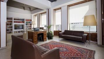 Un salon spacieux avec une grande télévision, un canapé en cuir et un tapis à motifs.