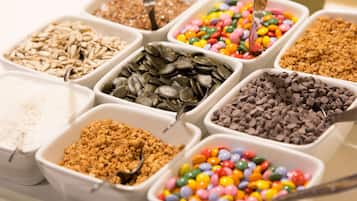 A variety of snack options in white containers, including sunflower seeds, chocolate chips, and colorful candies.