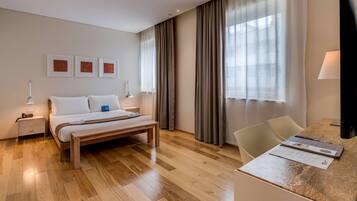 Una habitación de hotel con cama, mesitas de noche, escritorio y una silla.