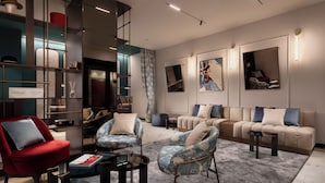 A modern hotel lobby with a red armchair, patterned armchairs, a beige sofa, and a glass coffee table. There are wall-mounted shelves with decorative items and framed artwork. - Puccini Hotel Milan, Tapestry Collection by Hilton (Milan)
