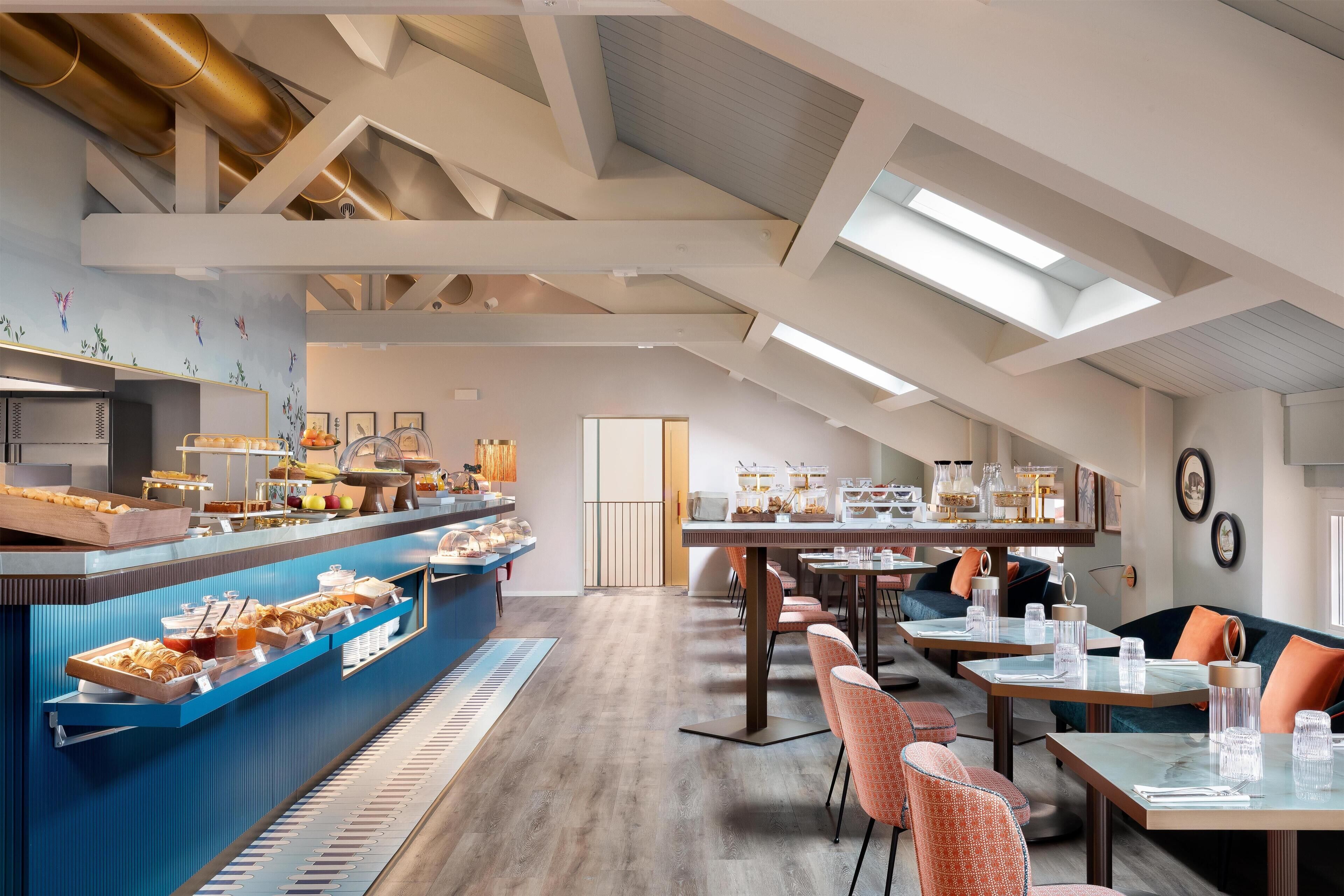 A modern dining area with a high ceiling, skylights, and a buffet with various food items.