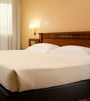 Una cama bien hecha con sábanas blancas en una habitación de hotel.