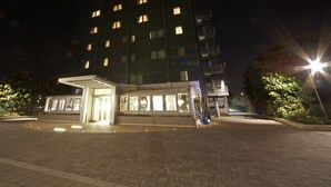 A multi-story hotel with a covered entrance and a well-lit lobby area. - Hotel Montini (Peschiera Borromeo)