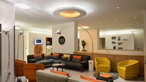 A modern living room with a sectional sofa, yellow armchairs, and a coffee table. - UNA Hotels Mediterraneo Milano (Milan)
