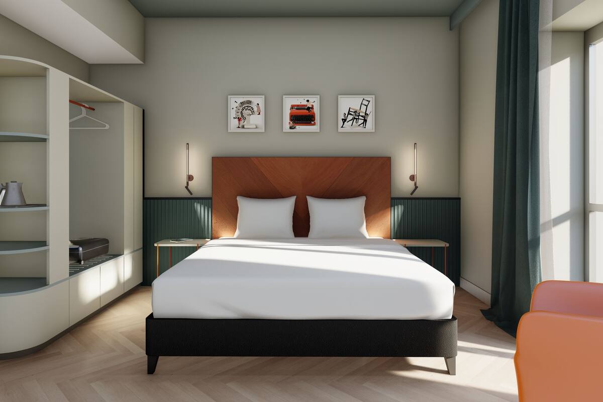 A modern hotel room with a bed, a wardrobe, a desk, and a chair.
