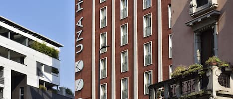 A hotel with a modern facade, multiple windows, and balconies with plants.