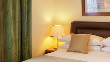Een hotelkamer met een bed, kussens, een lamp en gordijnen.