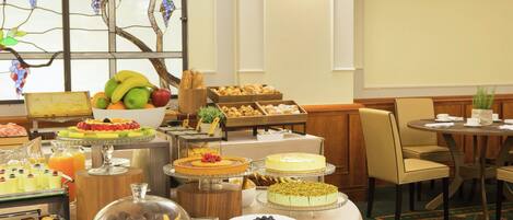 En buffet med forskellige retter og et bord med stole.