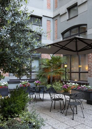 An outdoor patio area with tables and chairs, surrounded by potted plants and flowers. - Starhotels Business Palace (Milan)