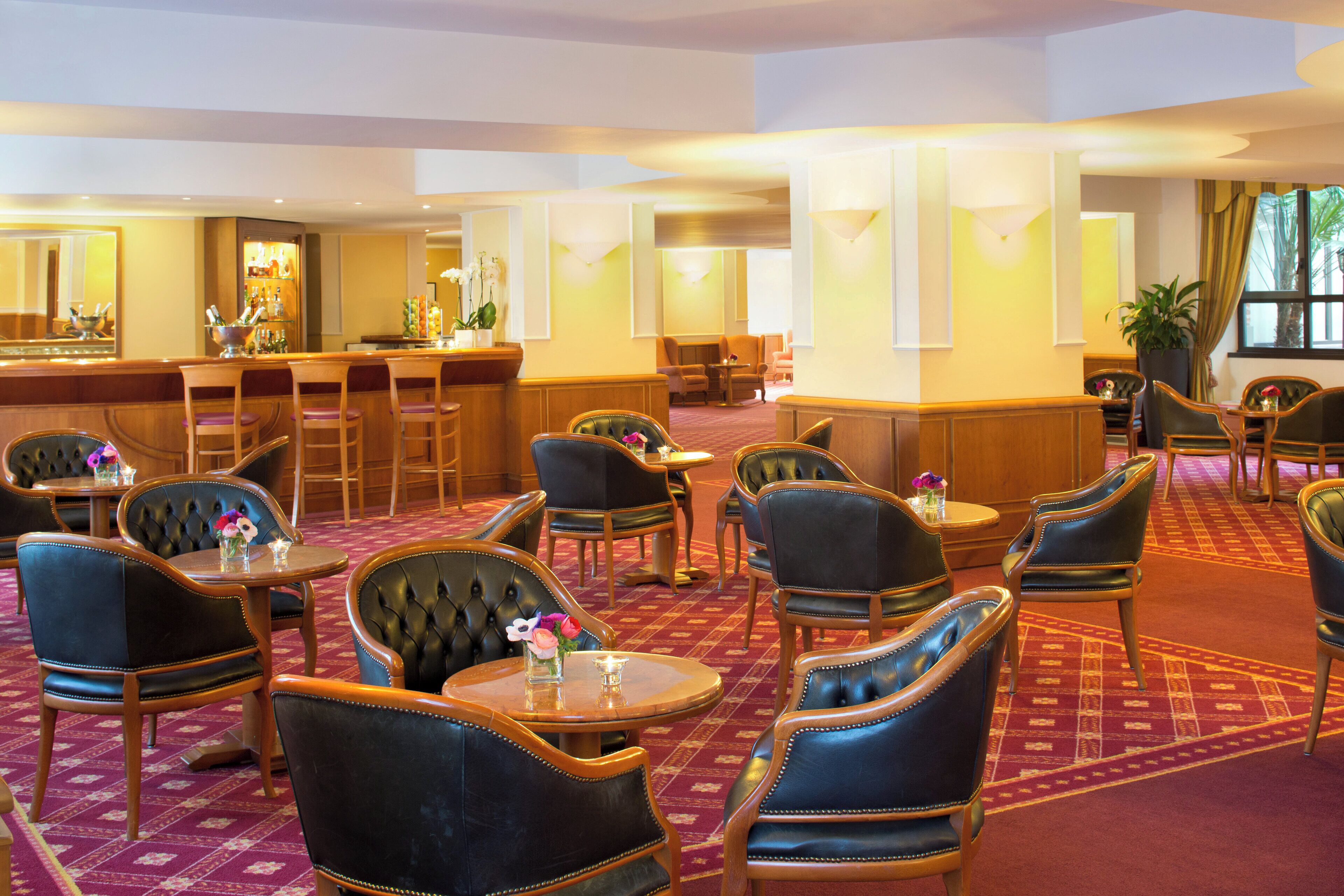 A hotel lobby with a bar area, multiple seating arrangements, and a carpeted floor.
