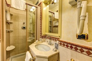 Un baño con ducha envuelta en vidrio, un lavabo con espejo y un perchero para toallas.