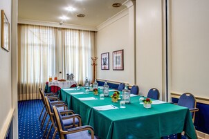 A conference room with a long table, chairs, and a window with curtains.