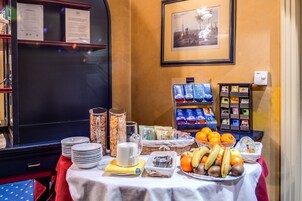 A breakfast buffet with plates, bowls, and a variety of fruits and beverages.