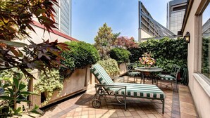 A patio area with a lounge chair, a small table, and potted plants. - Auriga Hotel (Milan)