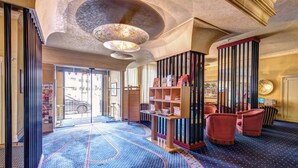 A hotel lobby with a patterned carpet, a reception desk, and seating area. - Auriga Hotel (Milan)