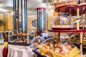 Un buffet con diversi prodotti da forno esposti in teche di vetro e cesti.