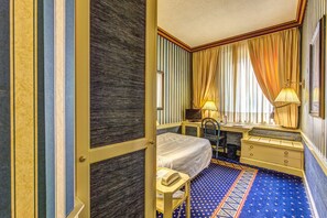 A hotel room with a bed, desk, chair, and a patterned carpet. - Auriga Hotel (Milan)