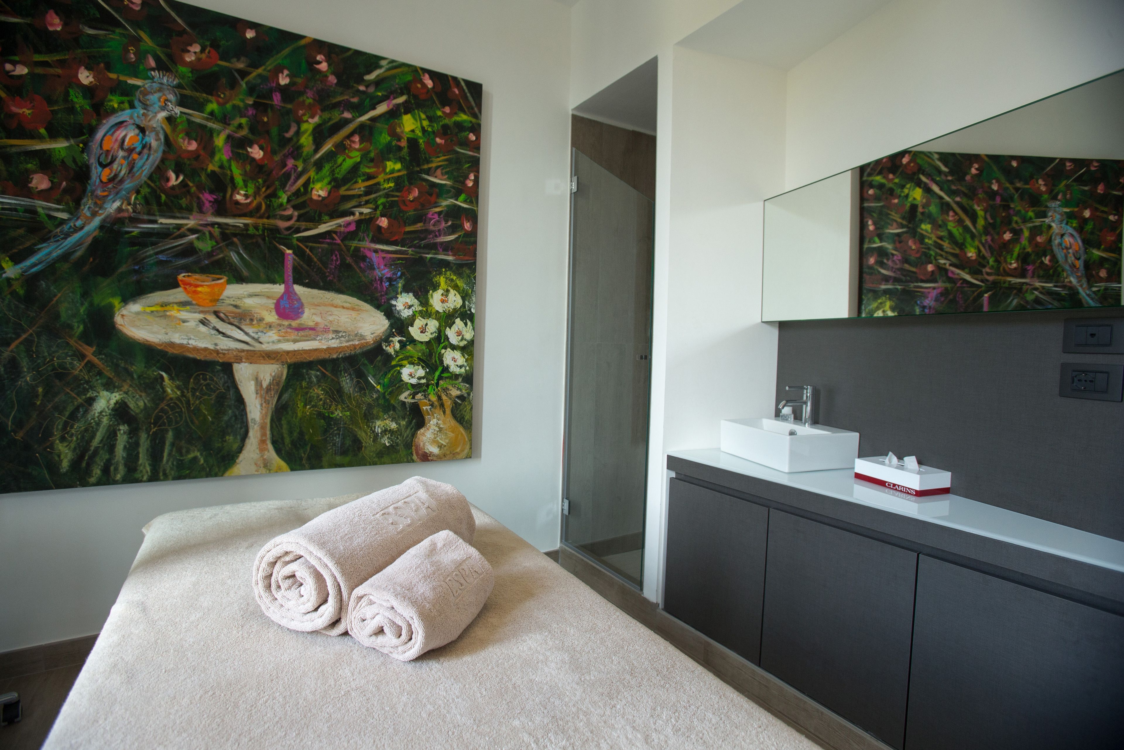 Ein modernes Badezimmer mit einem großen Gemälde, einem Waschbecken und einem Spiegel.