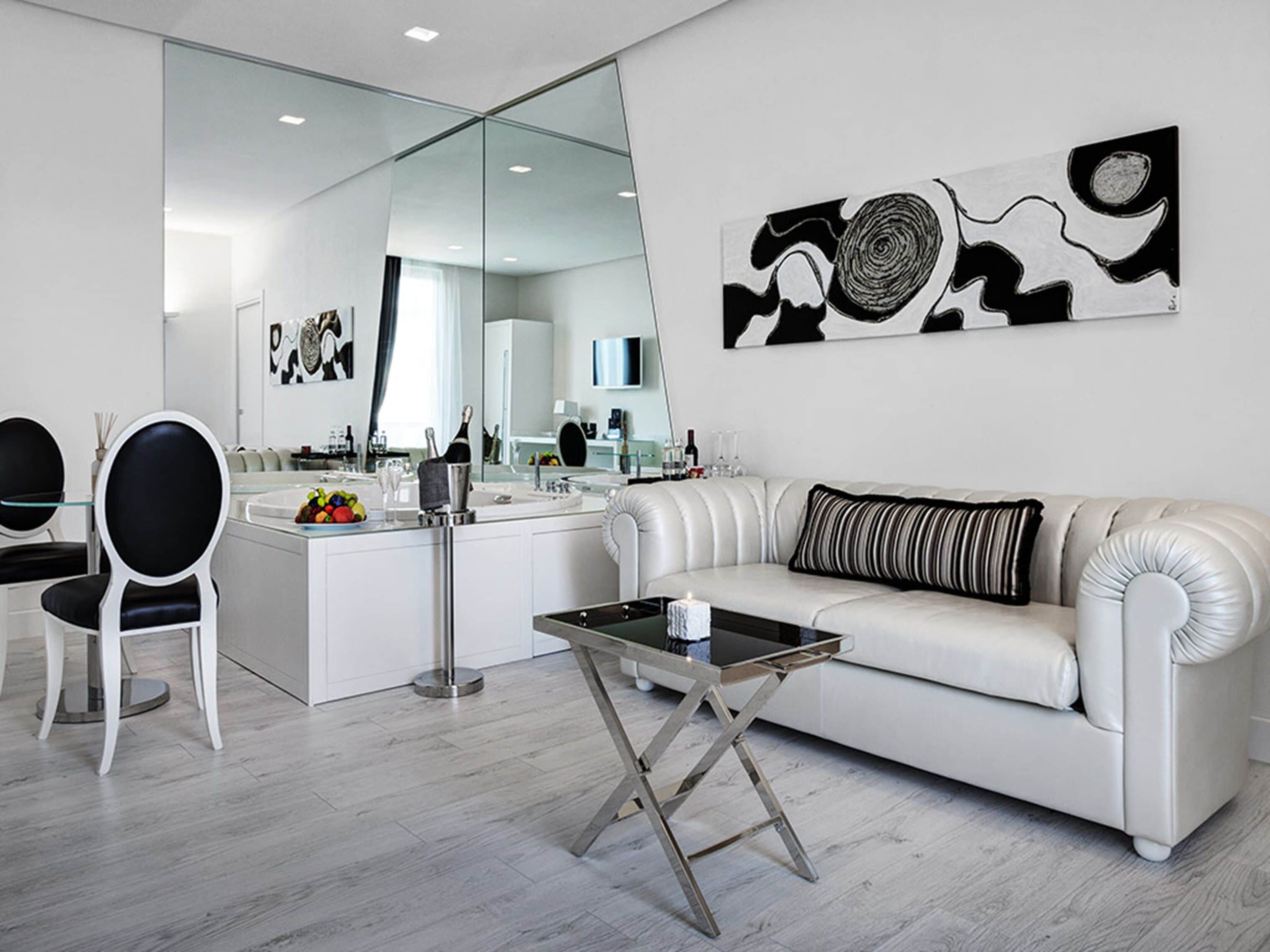 A modern living room with a white sofa, a glass coffee table, and a dining area with a white table and chairs.