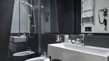 Une salle de bain moderne dotée d’une douche à parois de verre, d’un bidet, d’un meuble-lavabo avec miroir et d’un porte-serviettes.