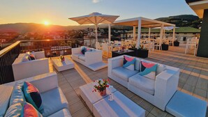 A rooftop terrace with outdoor seating and a view of the city at sunset. - LHP Hotel Montecatini Palace & SPA (Montecatini Terme)