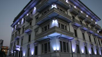 Ein mehrstöckiges Gebäude mit klassischer Architektur, mit Balkonen und beleuchteten Fenstern.