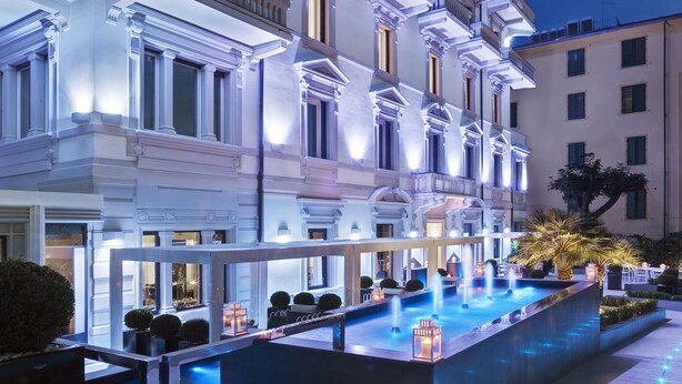 A well-lit hotel facade with multiple balconies and a central water feature. - LHP Hotel Montecatini Palace & SPA (Montecatini Terme)